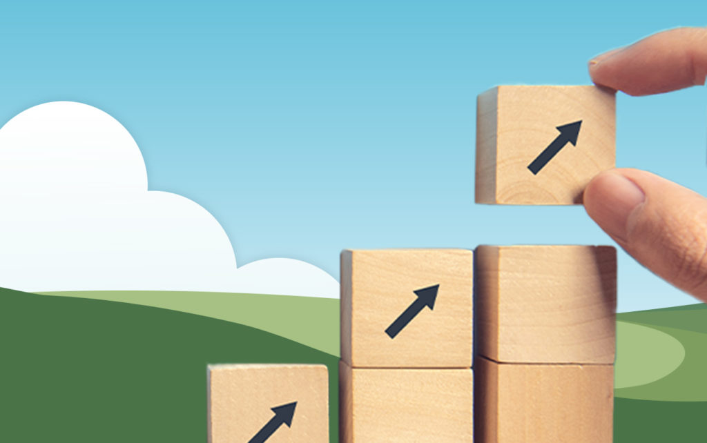 Building blocks stacked higher and higher in front of illustrated grass